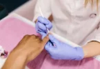 Woman performing ASMR Koni remove polish routine with soft tools and foil wraps for relaxing Korean-style nail care.
