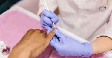 Woman performing ASMR Koni remove polish routine with soft tools and foil wraps for relaxing Korean-style nail care.